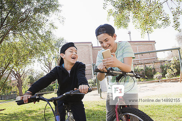 Jungen schauen auf ihren Fahrrädern auf ihr Smartphone