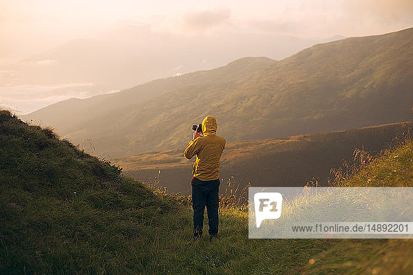 Mann in gelber Jacke beim Fotografieren in den Karpaten