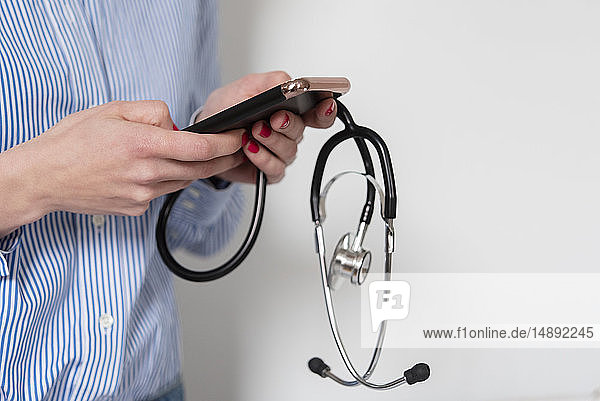 Arzt hält Stethoskop und Smartphone