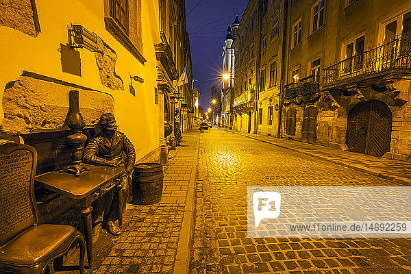 Skulptur eines Mannes  der nachts am Tisch sitzt  in Lviv  Ukraine