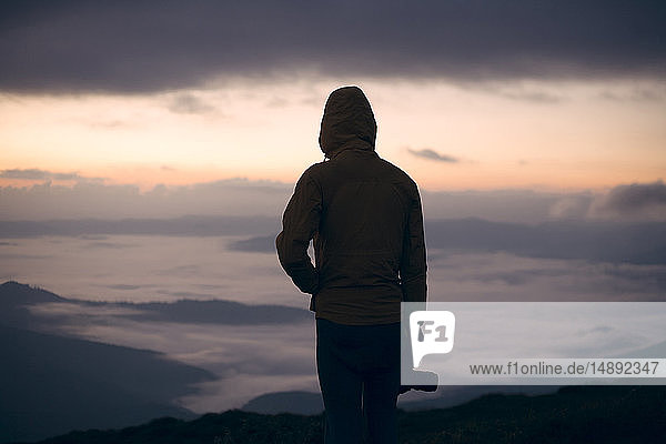 Silhouette eines jungen Mannes mit Kamera bei Sonnenuntergang im Karpatengebirge