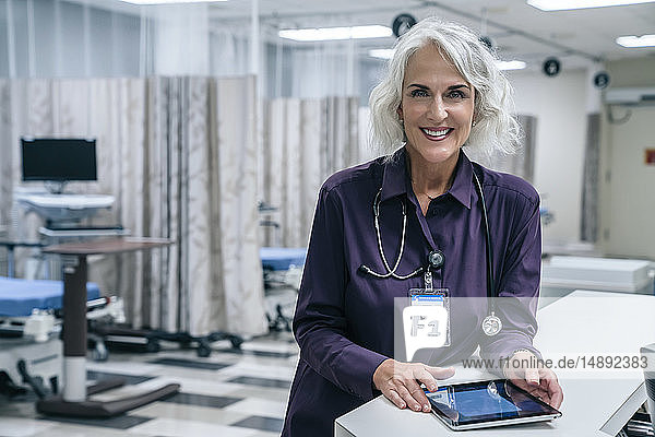 Lächelnder Arzt mit digitalem Tablet im Krankenhaus