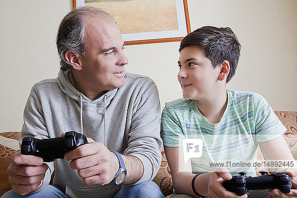 Vater und Sohn im Teenageralter spielen ein Videospiel