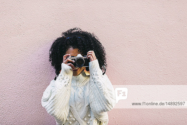 Junge Frau fotografiert vor einer rosa Wand