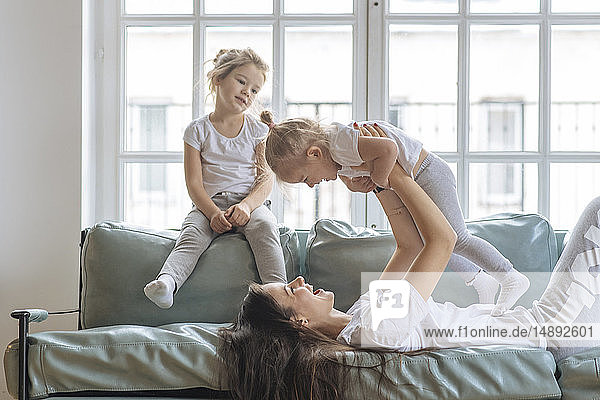 Mother playing with her daughters on sofa