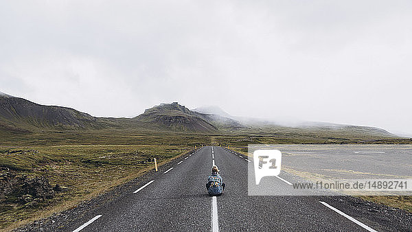 Frau sitzt auf der Autobahn in Island