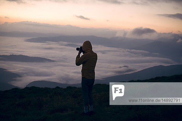Silhouette eines jungen Mannes  der bei Sonnenuntergang im Karpatengebirge fotografiert