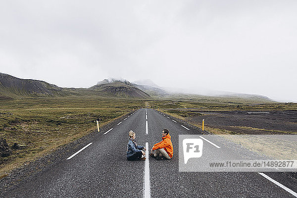 Couple sitting on highway in Iceland