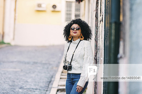 Junge Frau mit Sonnenbrille und Kamera auf der Straße