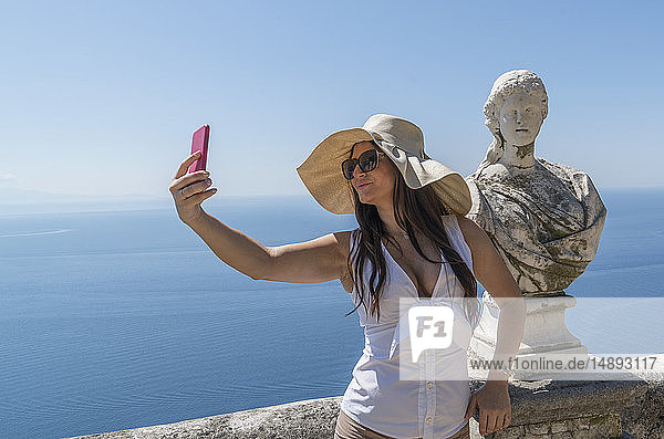 Frau macht Selfie bei Skulptur-Büste