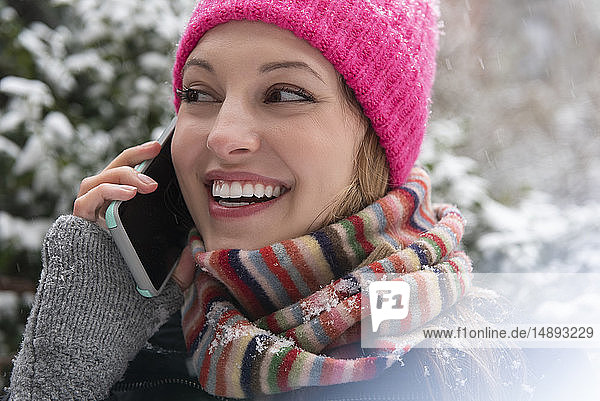 Junge Frau beim Telefonieren im Schnee