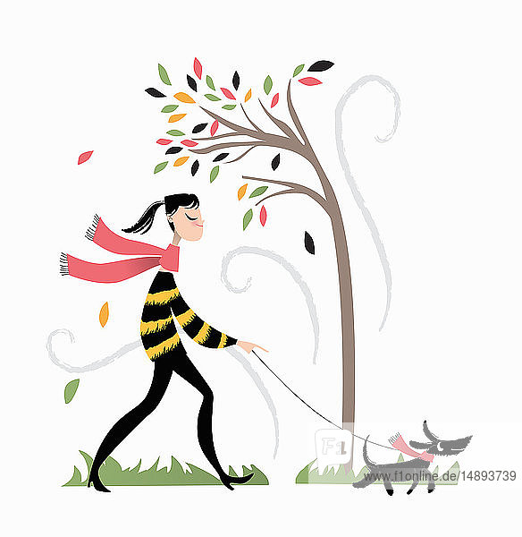 Frau geht an einem windigen Herbsttag mit dem Hund spazieren