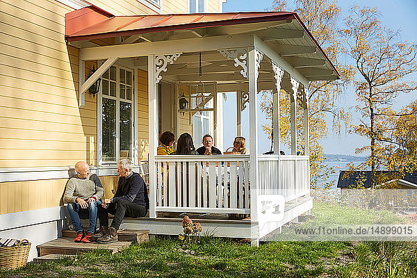 Freunde unterhalten sich  während sie auf der Veranda vor dem Herrenhaus sitzen