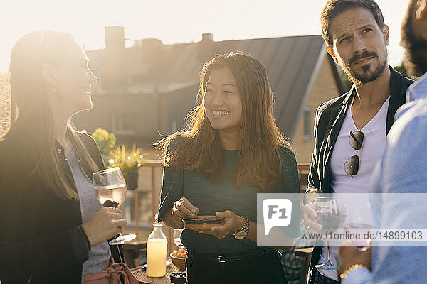 Cheerful friends having social gathering on terrace during sunset