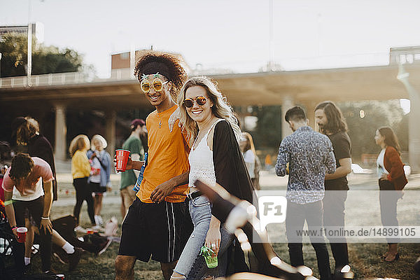 Portrait of smiling friends walking together with people in background