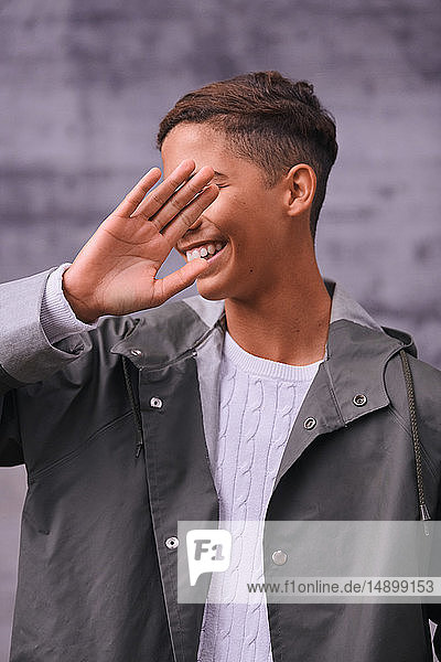 Cheerful teenage boy showing stop gesture while standing outdoors