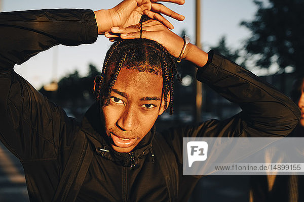 Porträt eines Teenagers  der bei Sonnenuntergang in der Stadt geflochtene Haare bindet