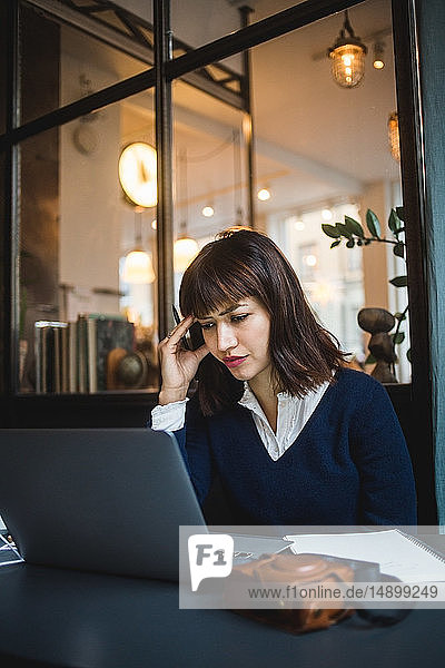 Businesswoman working at desk while using laptop in creative office