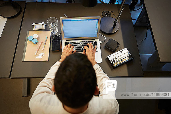 Hochwinkelansicht eines Geschäftsmannes mit Laptop am Schreibtisch im Kreativbüro