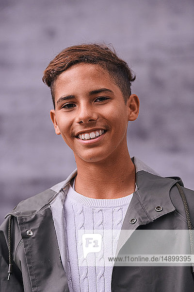 Porträt eines lächelnden Teenagers in Regenmantel auf dem Spielplatz