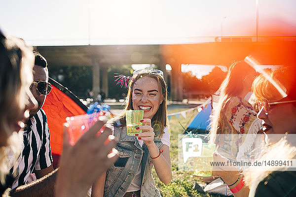 Lächelnde Freunde geniessen Getränke bei Musikkonzert im Sommer