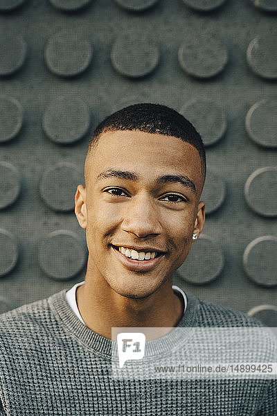 Portrait of smiling teenage boy standing against wall