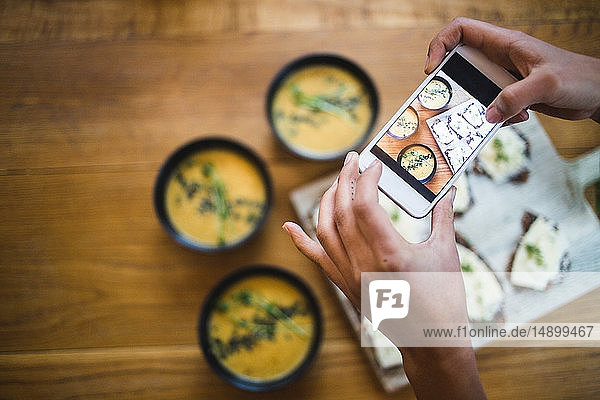 Hände einer Bloggerin  die im Kreativbüro Kürbissuppe und Knäckebrot per Smartphone fotografiert