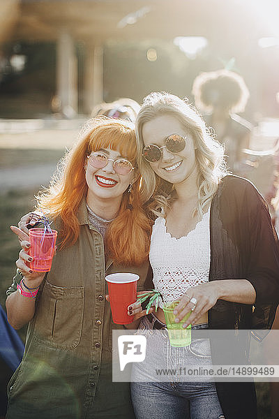 Portrait of smiling male friends enjoying drinks in concert on sunny day