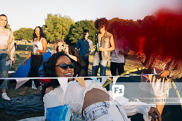 Smiling woman performing limbo dance while enjoying with friends at music festival