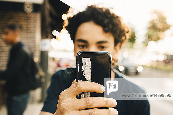 Jugendlicher Junge benutzt Mobiltelefon in der Stadt
