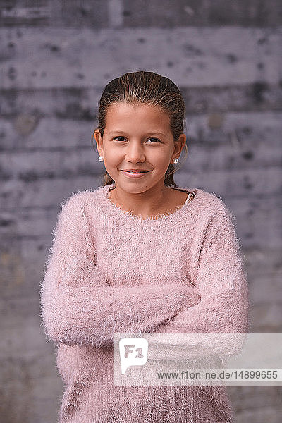 Portrait of smiling girl with arms crossed standing outdoors