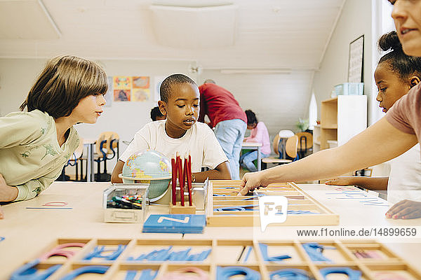 Schüler lernen Rechtschreibung am Tisch durch den Lehrer im Klassenzimmer