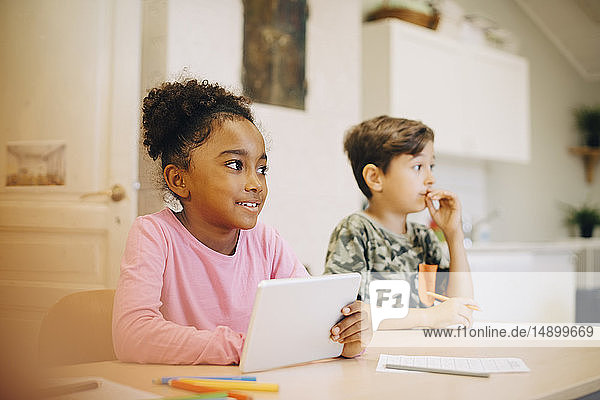 Junge lernt durch digitales Tablett  während er mit einem Freund im Klassenzimmer sitzt