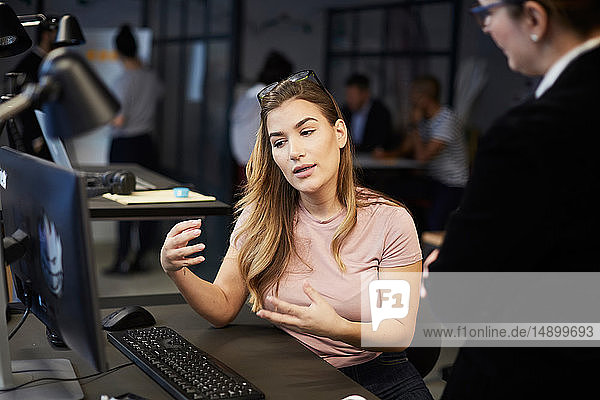 Creative businesswoman explaining bank manager at desk in creative office