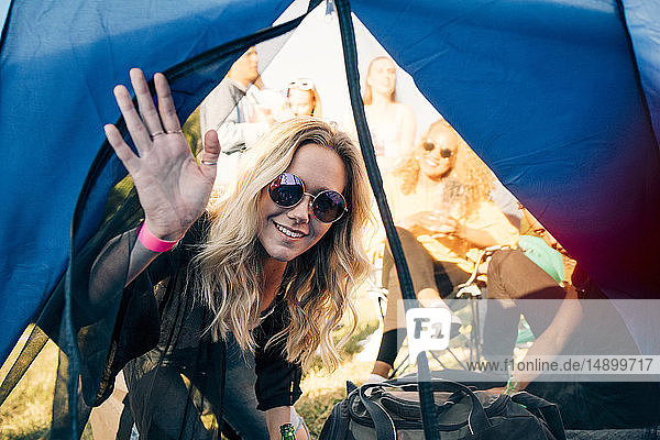 Porträt einer lächelnden Frau mit Freunden  die im Zelt auf das Festival schauen