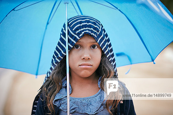 Porträt eines Mädchens mit Regenschirm  das während der Regenzeit einen Regenmantel trägt
