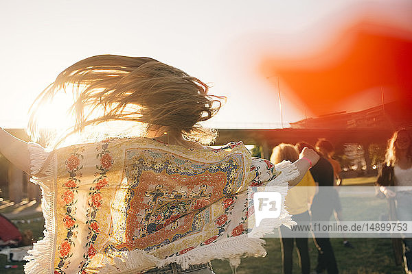 Rear view of woman tossing hair while enjoying in music concert during summer