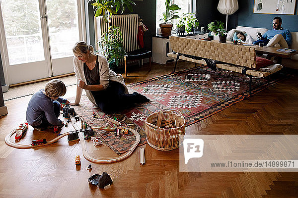 Mutter und Tochter spielen zu Hause im Wohnzimmer mit der Eisenbahn