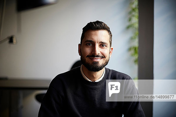 Portrait of confident male entrepreneur sitting in creative office