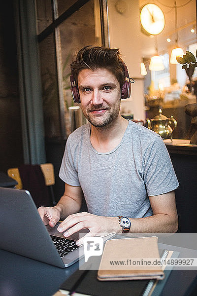 Porträt eines lächelnden Geschäftsmannes mit Laptop am Schreibtisch im Büro