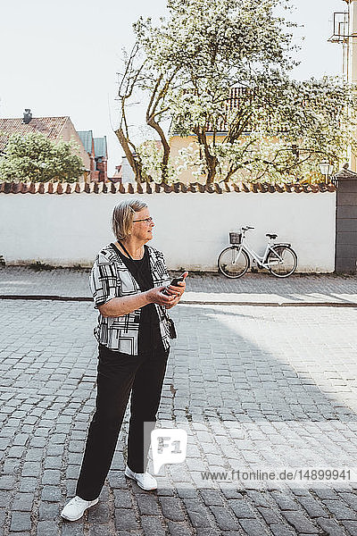 Ältere weibliche Touristin in voller Länge auf der Straße in der Stadt stehend