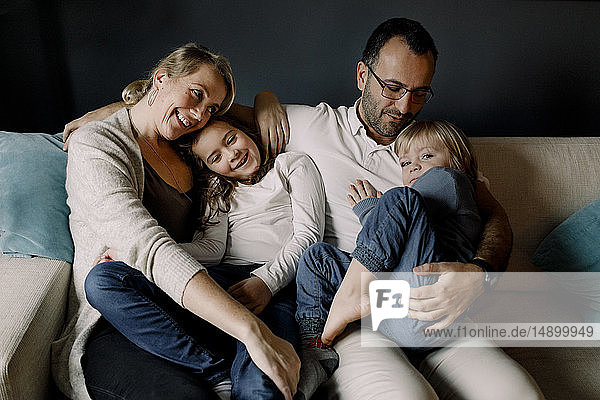 Glückliche  liebevolle Familie  die zu Hause auf der Couch zusammensitzt
