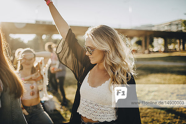 Young woman dancing in music festival on sunny day