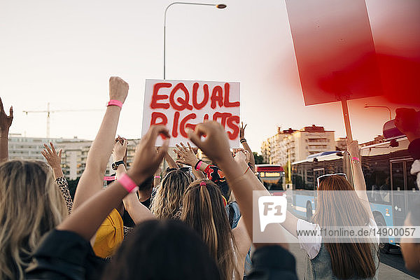 Rückansicht von Frauen mit Transparenten  die für Gleichberechtigung in der Stadt marschieren