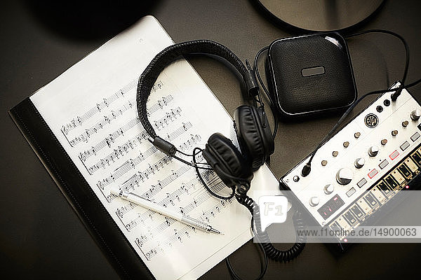 Direkt über der Aufnahme von Kopfhörern auf Notenblättern mit Tonausrüstung auf dem Schreibtisch im Büro