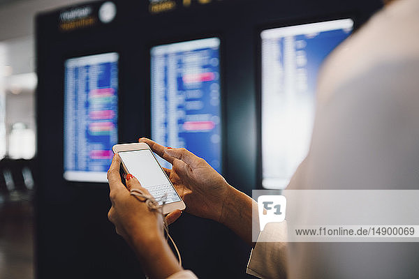 Midsection of businesswoman using phone while standing at airport