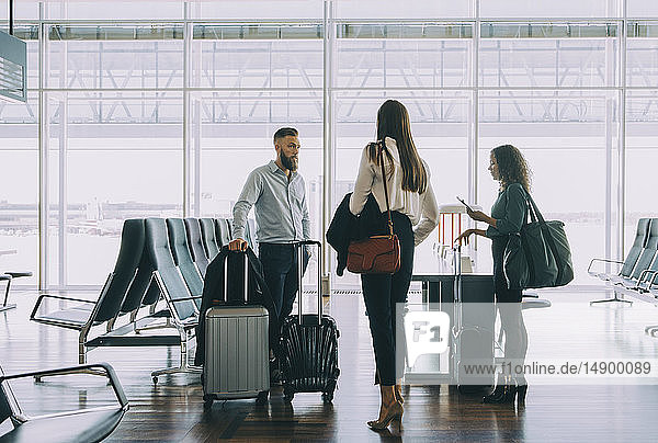 Multi-ethnische Geschäftskollegen stehen mit Gepäck im Abflugbereich des Flughafens