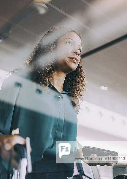 Niedriger Blickwinkel auf eine Geschäftsfrau  die ein Smartphone hält  während sie am Flughafen steht