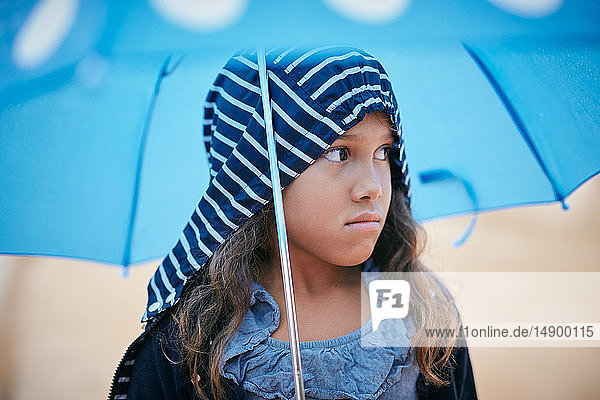 Girl with umbrella looking away during rainy season