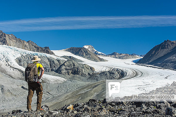 A man walks in Gulkana Glacier Valley in the Eastern Alaska Range in South-central Alaska on a sunny summer afternoon; Alaska  United States of America
